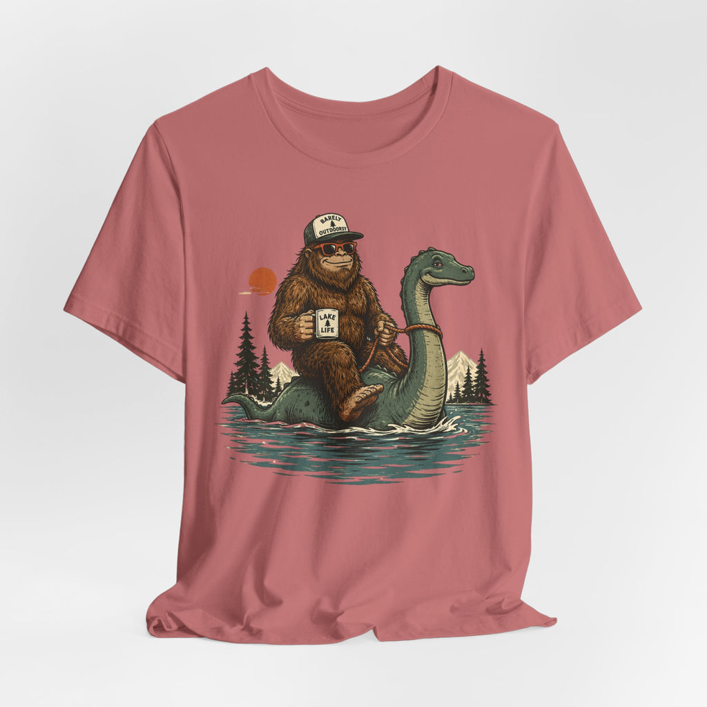 Flat lay of Barely Outdoorsy Bigfoot Nessie lake life tee, heather ice blue unisex crew neck, Bella Canvas 3001