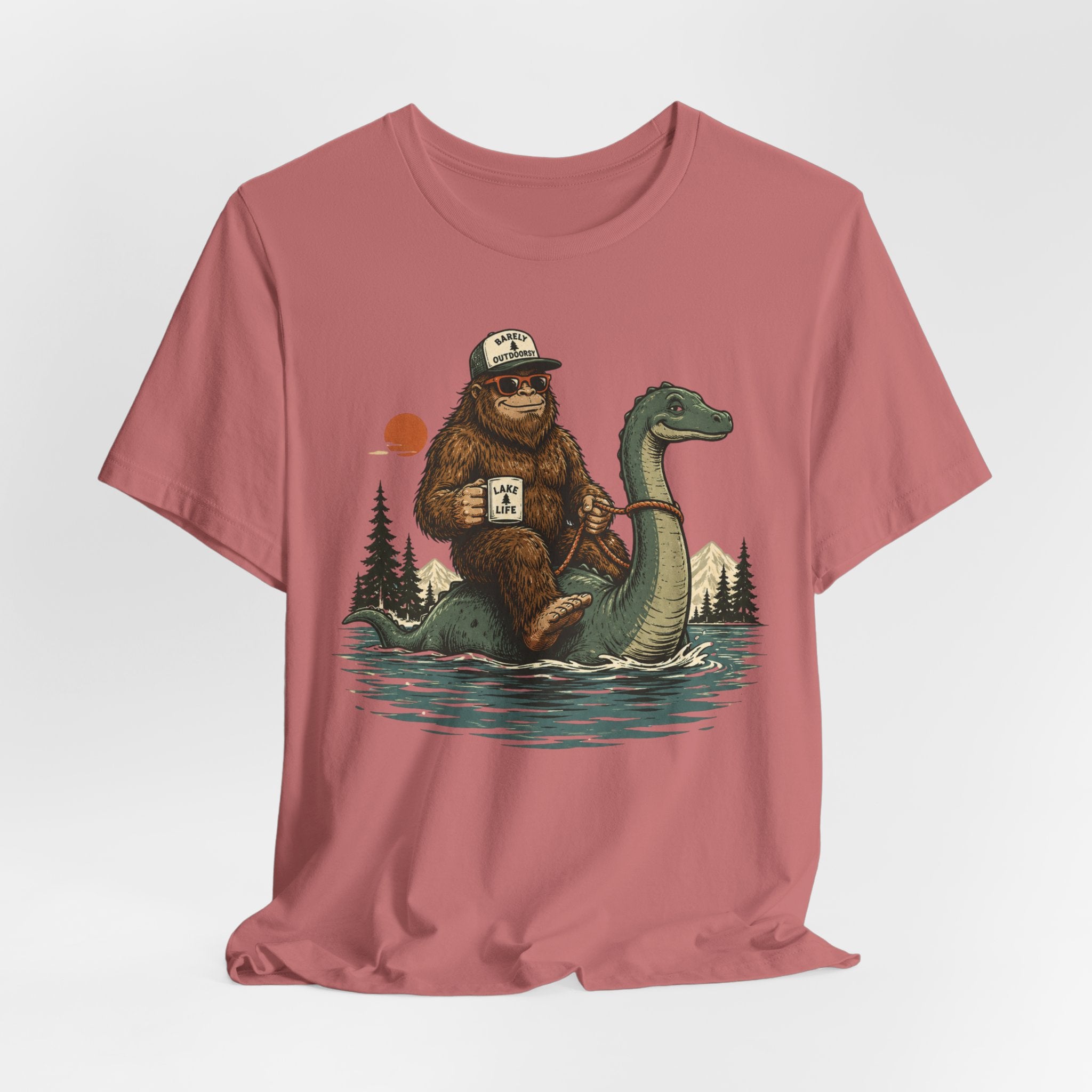 Flat lay of Barely Outdoorsy Bigfoot Nessie lake life tee, heather ice blue unisex crew neck, Bella Canvas 3001