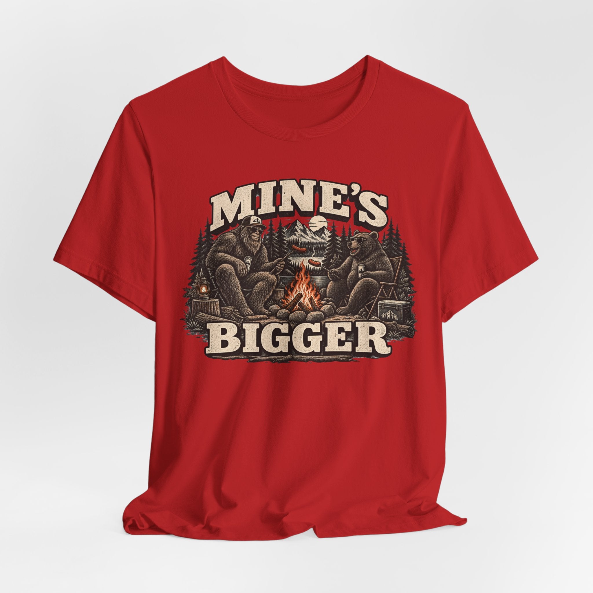 Mine's Bigger Funny Bigfoot T-Shirt flat lay Athletic Heather - unisex crew neck Bigfoot campfire graphic tee, Barely Outdoorsy